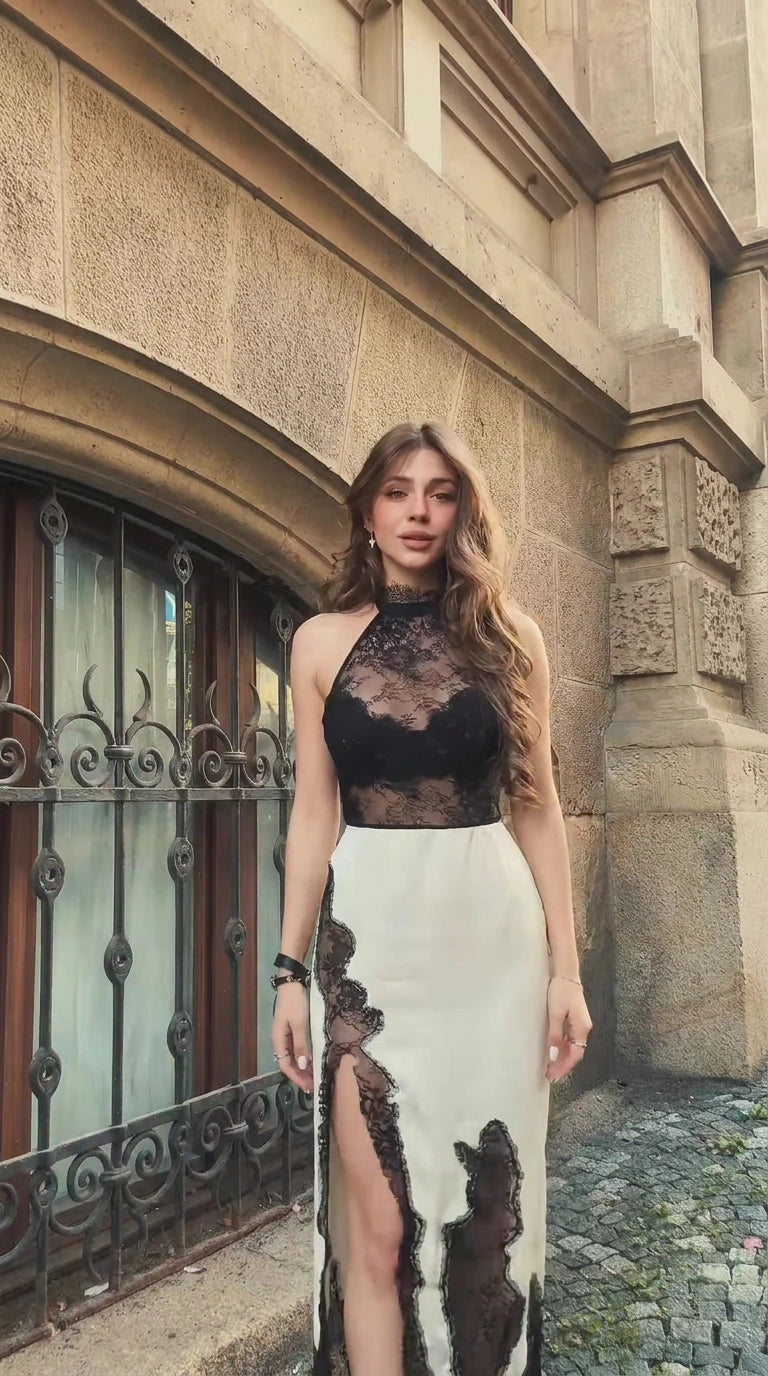 Front view of woman wearing ivory and black lace halter high slit maxi dress