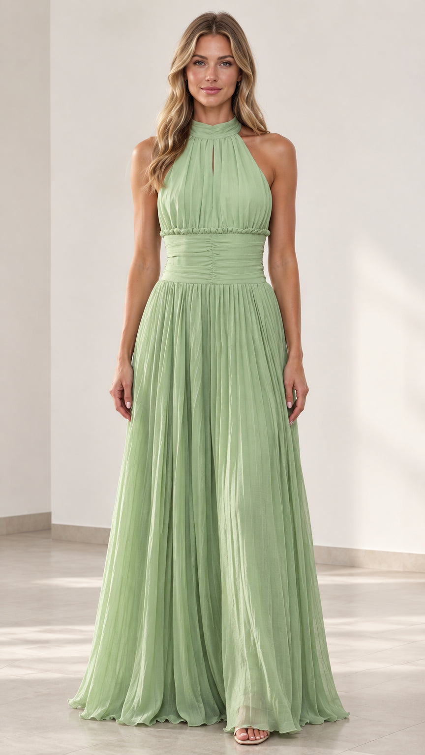 Front view of woman wearing sage green halter-neck pleated maxi dress