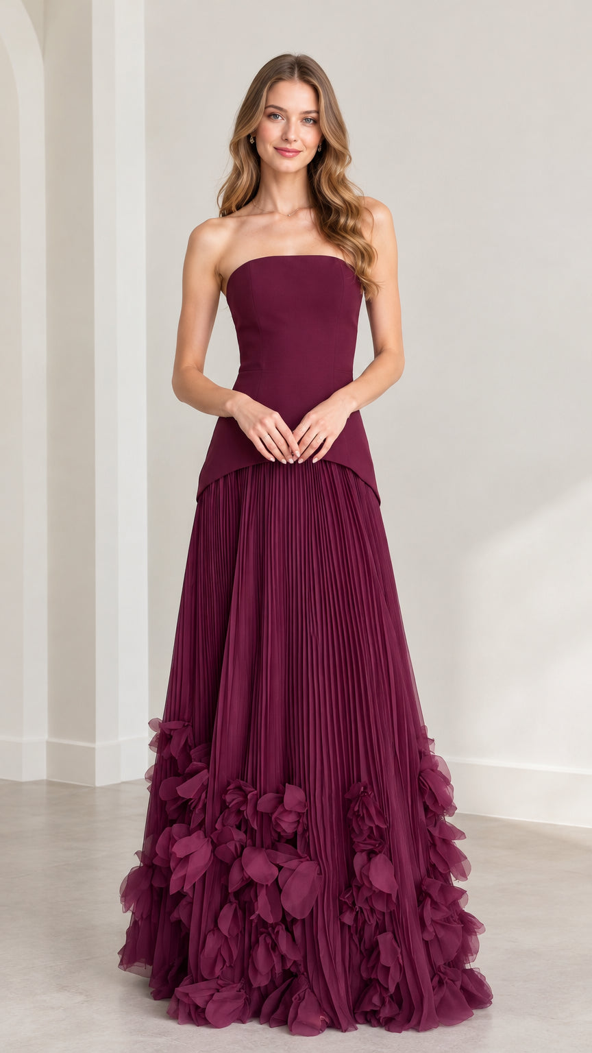 Front view of model wearing burgundy strapless pleated maxi dress with 3D petal hem