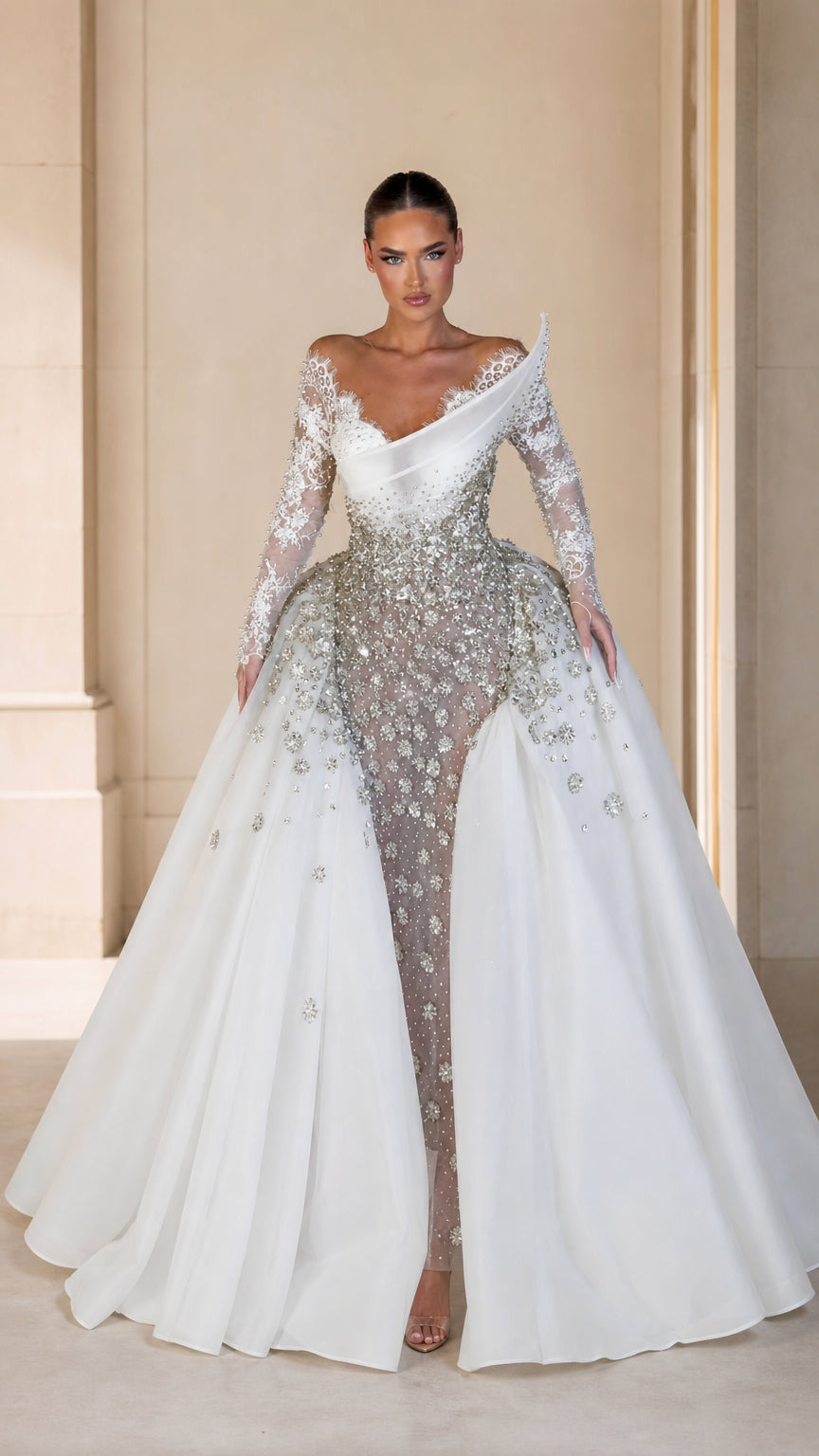 Front view of model wearing white asymmetrical beaded evening gown with dramatic overskirt