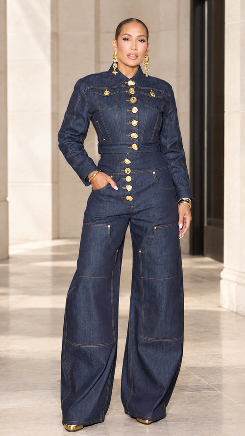 Front full view of woman wearing dark blue wide leg denim jumpsuit with gold buttons
