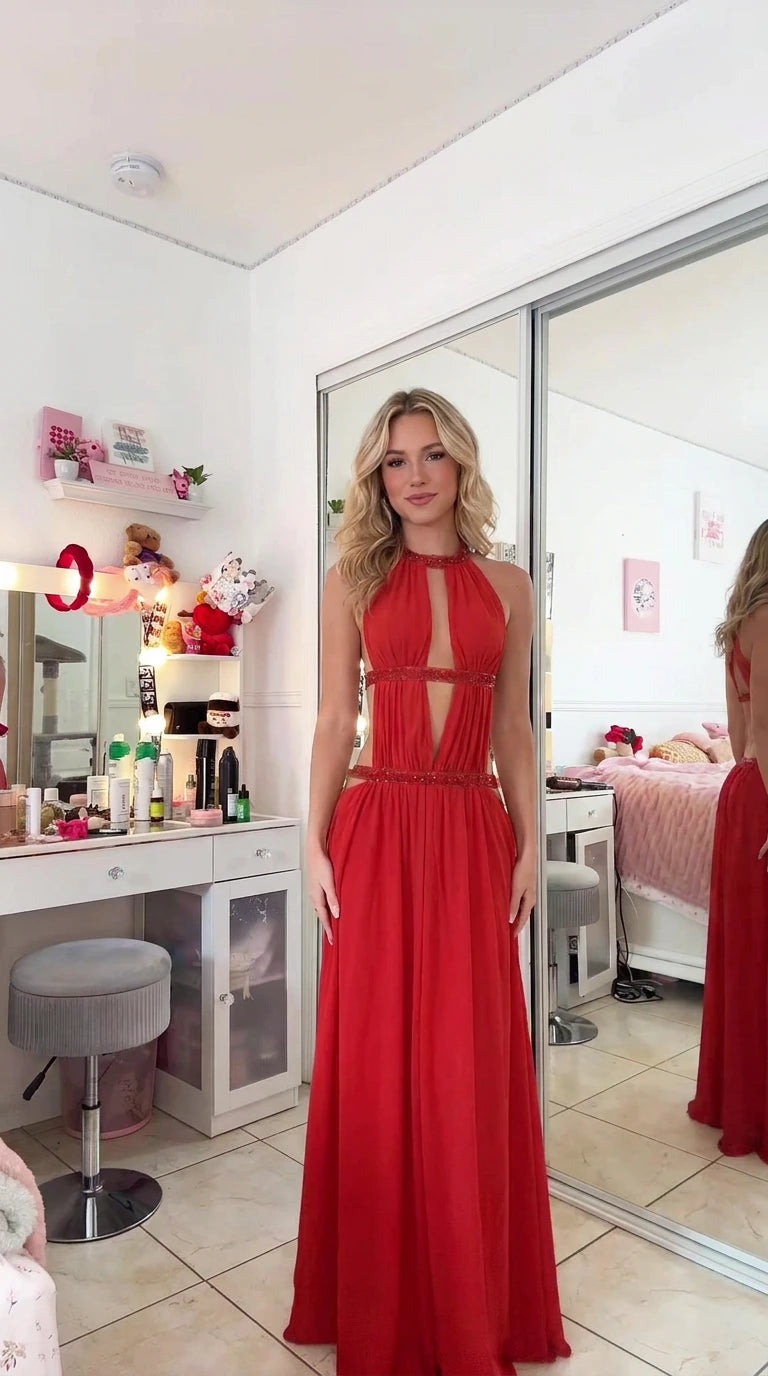 Full front view of model wearing a floor-length red halter cutout evening gown with beaded waist trim
