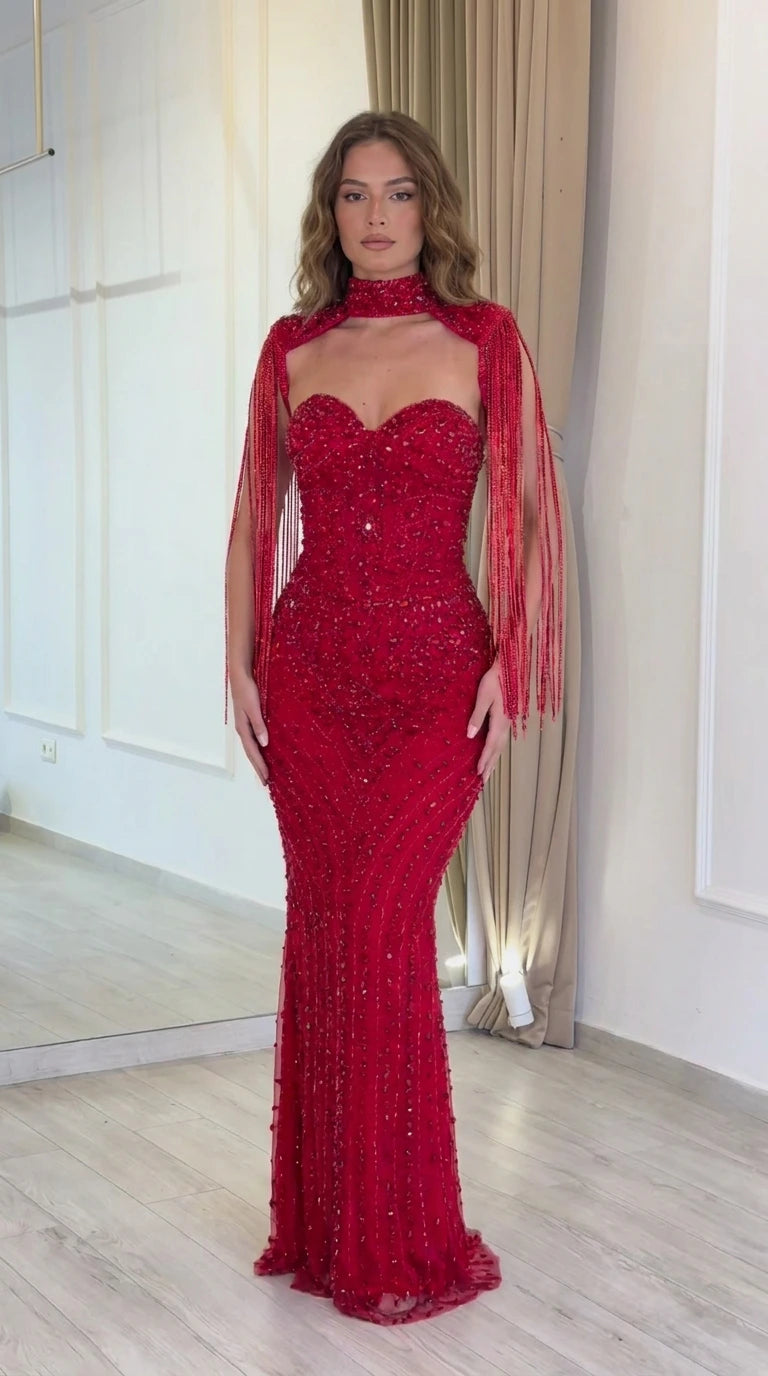Front view of model wearing a red beaded sweetheart evening gown with fringe sleeve capelet