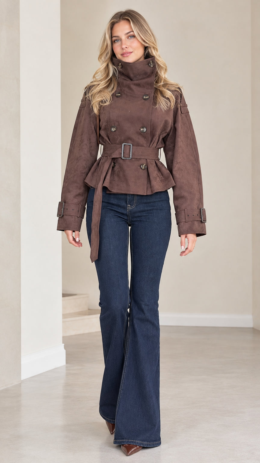 Front view of model wearing brown high neck belted cropped double breasted trench jacket with flare jeans