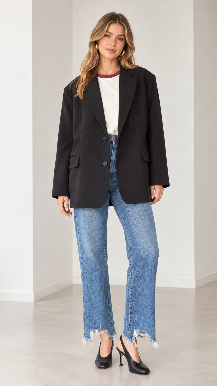 Model wearing a black oversized single-breasted blazer with blue jeans and heels, front view