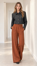 Full front view of model wearing black cropped diamond-quilted jacket and rust wide-leg trousers