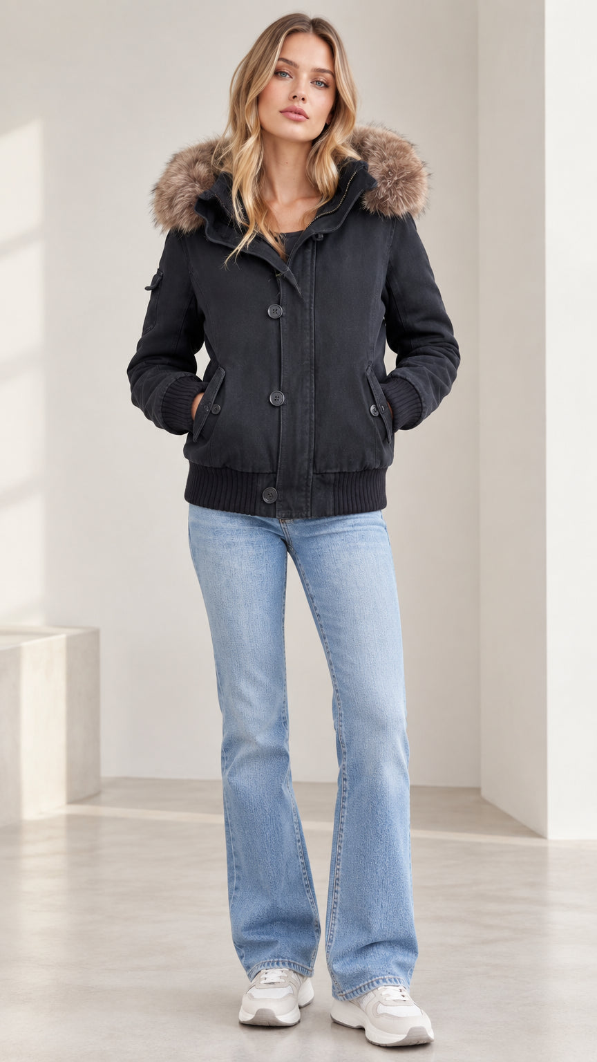 Front view of model wearing black women's faux fur hooded winter bomber jacket with jeans