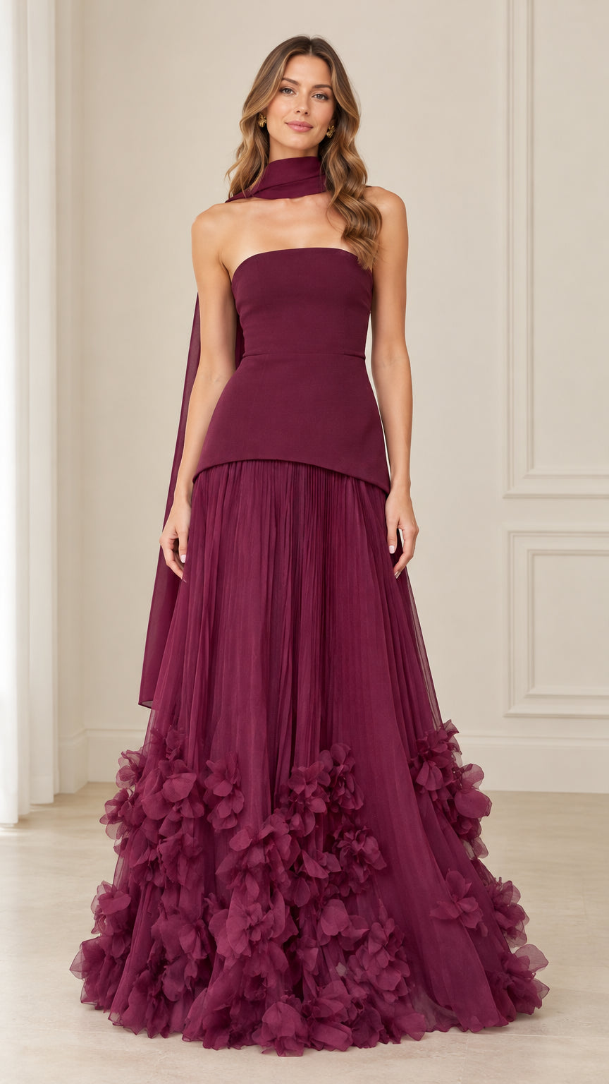 Front full-length view of model wearing burgundy strapless peplum evening gown with matching neck scarf and 3D floral tulle hem