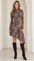 Front full-length view of model wearing mocha brown floral mock neck asymmetrical midi dress with knee-high boots