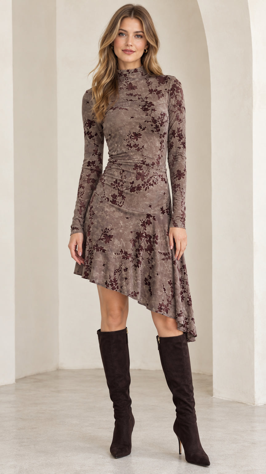 Front full-length view of model wearing mocha brown floral mock neck asymmetrical midi dress with knee-high boots