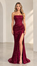 Front full-length view of woman wearing burgundy strapless sequin evening gown with high leg slit