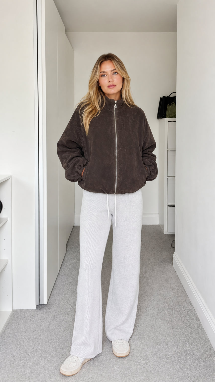 Front full-body view of model wearing dark brown fleece zip-up jacket with white sweatpants