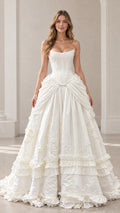 Front view of model wearing ivory strapless corset tiered ruffle ball gown
