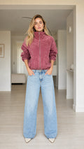 Full front view of model wearing dusty rose plush zip-up bomber jacket with wide-leg jeans