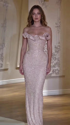 Front view of model wearing a blush pink off-the-shoulder beaded evening gown with rosette neckline