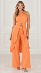 Model wearing orange halter neck split drape top and matching wide leg pants set, front view
