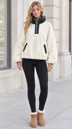 Front full view of woman wearing white sherpa fleece half-zip jacket with black stand collar and black leggings