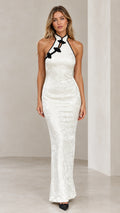 Front view of model wearing white halter mandarin collar jacquard maxi dress with black frog button accents