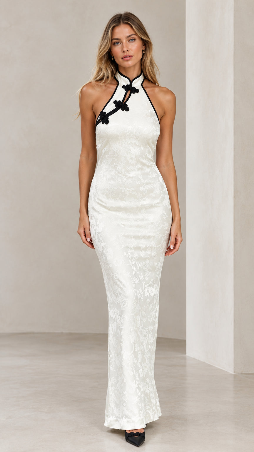 Front view of model wearing white halter mandarin collar jacquard maxi dress with black frog button accents