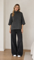 Front view of model wearing dark grey turtleneck half sleeve knit sweater with wide-leg jeans