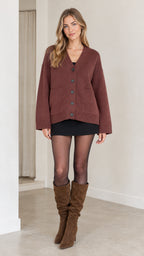 Model wearing a relaxed brown V-neck knit cardigan with button front, black skirt, and knee-high boots