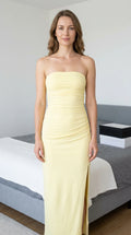 Front view of woman wearing butter yellow strapless ruched maxi dress with side slit