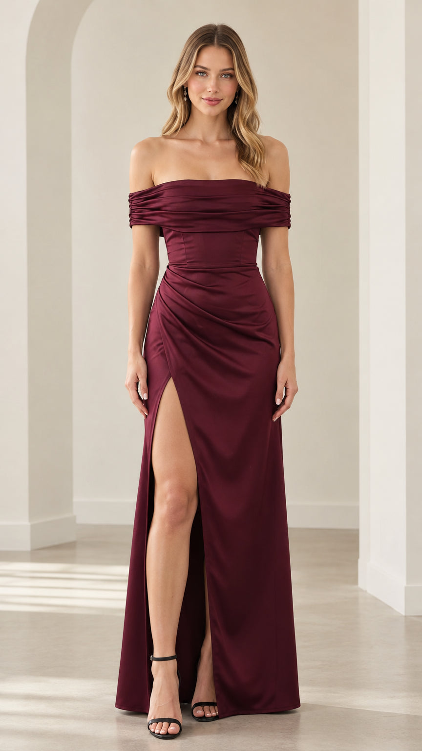 Front full-length view of woman in burgundy off-the-shoulder ruched satin maxi dress with high side slit