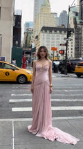 Front full-length view of woman in blush pink strapless pleated chiffon evening gown with train