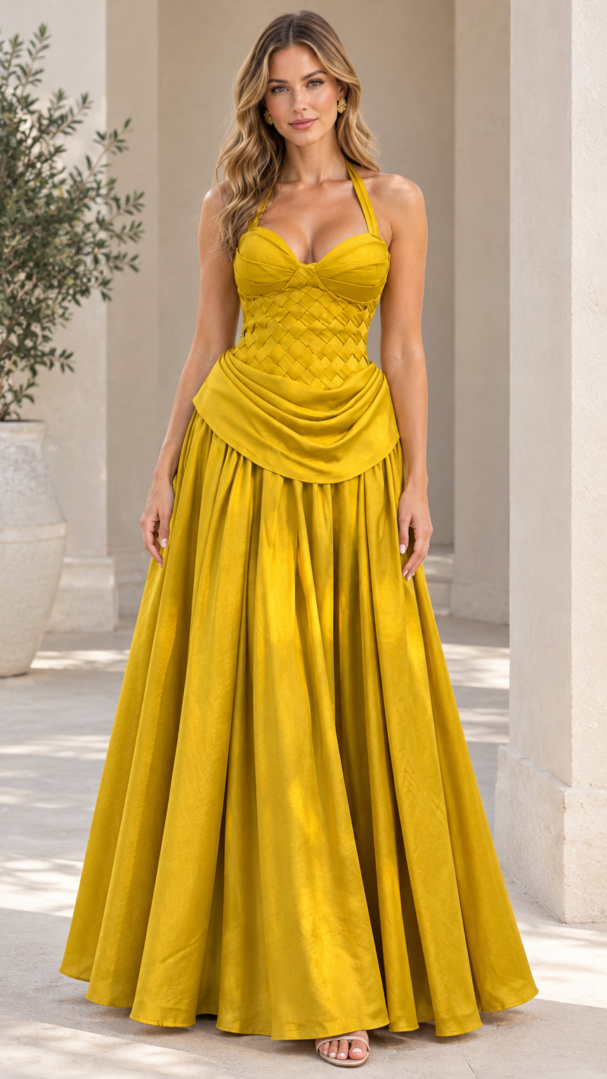 Front view of model wearing elegant yellow halter neck evening gown with woven bodice and pleated skirt