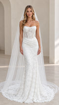 Front view of model wearing white strapless sheer corset mermaid wedding gown with long veil
