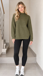 Front view of model wearing olive green mock neck knit sweater with black leggings