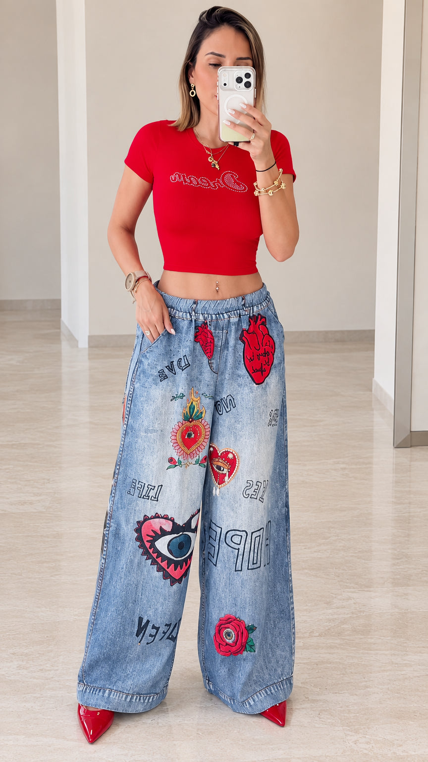 Front full view of woman wearing red cropped t-shirt and blue wide-leg graphic printed pants