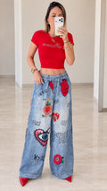 Front full view of woman wearing red cropped t-shirt and blue wide-leg graphic printed pants