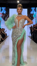 Front runway view of silver sequin evening gown with mint green feather sleeve and slit trim