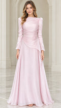 Front view of woman wearing blush pink long sleeve ruched evening gown with beaded waist accent