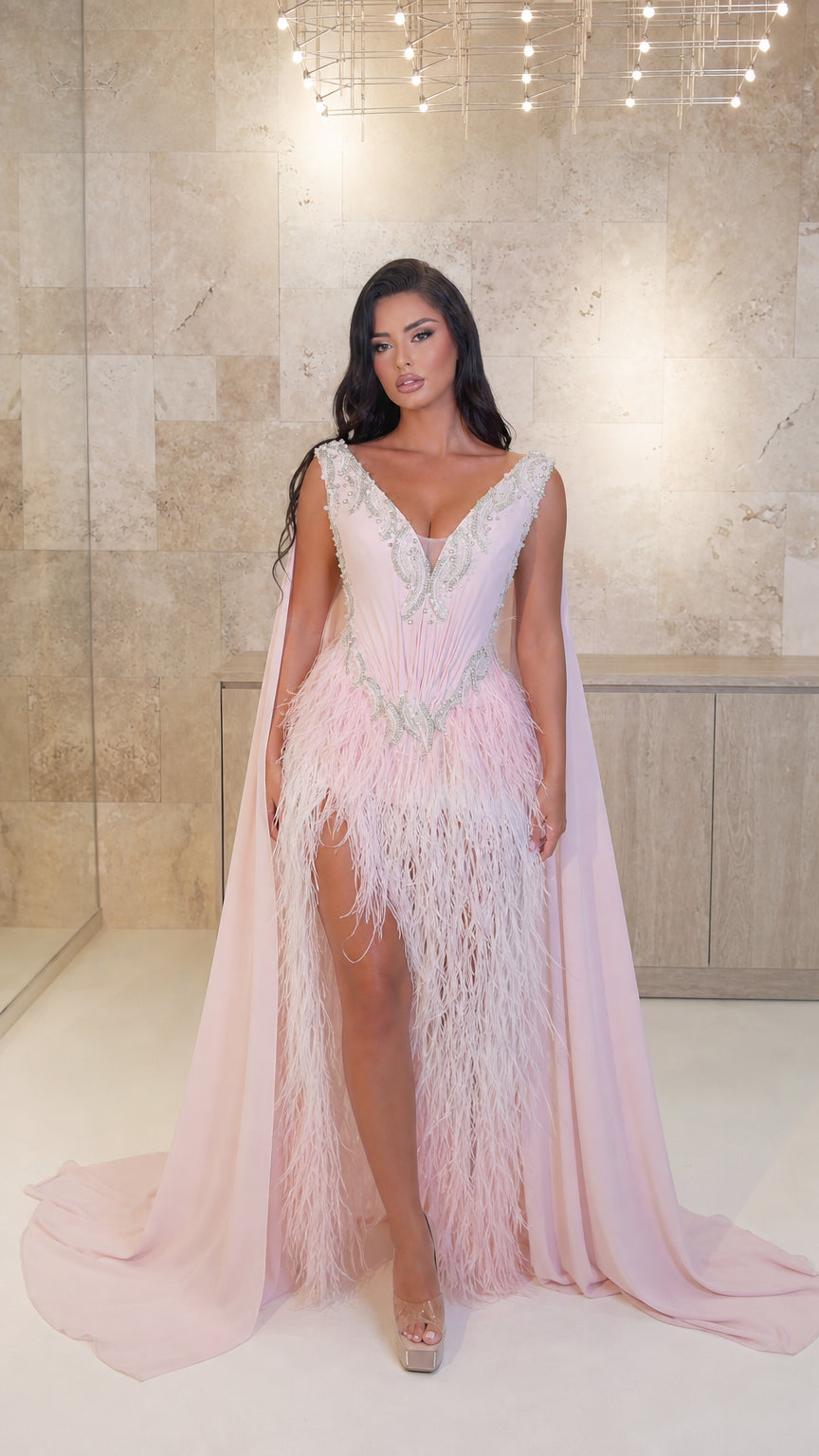 Model wearing Blush Pink embellished cape evening gown with feather fringe skirt - front view