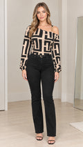 Front full-length view of model wearing beige and black geometric asymmetrical chain strap blouse with black jeans