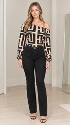 Front full-length view of model wearing beige and black geometric asymmetrical chain strap blouse with black jeans