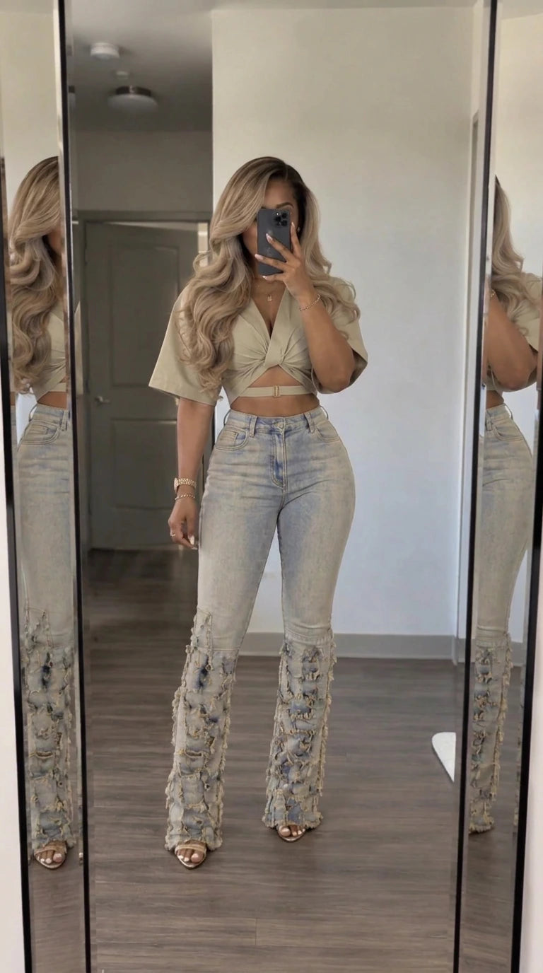 Front view of woman wearing beige wrap crop top and heavily fringed flare denim jeans