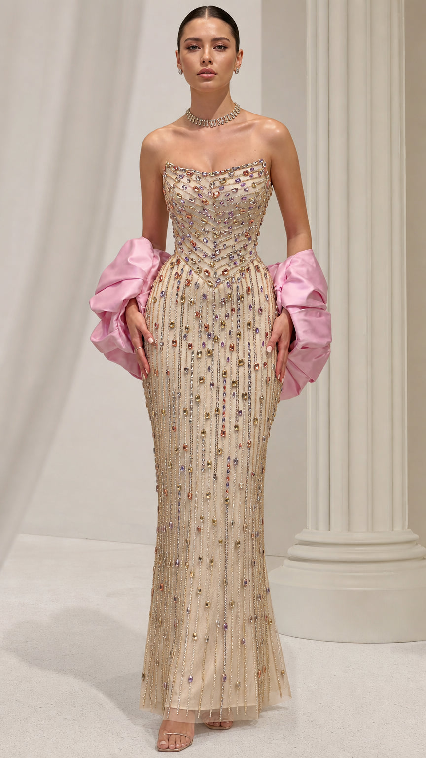 Front view of model wearing a champagne strapless beaded column evening gown with pink puff sleeves