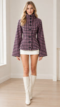 Front view of model wearing pink and black plaid high-neck fitted jacket with knee-high boots