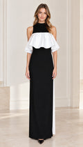 Front view of model wearing black high neck column maxi dress with white contrast ruffle overlay
