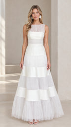 Front view of model wearing floor-length white sleeveless tiered evening gown with illusion neckline