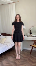 Front view of model wearing black tweed short sleeve top and bubble mini skirt set