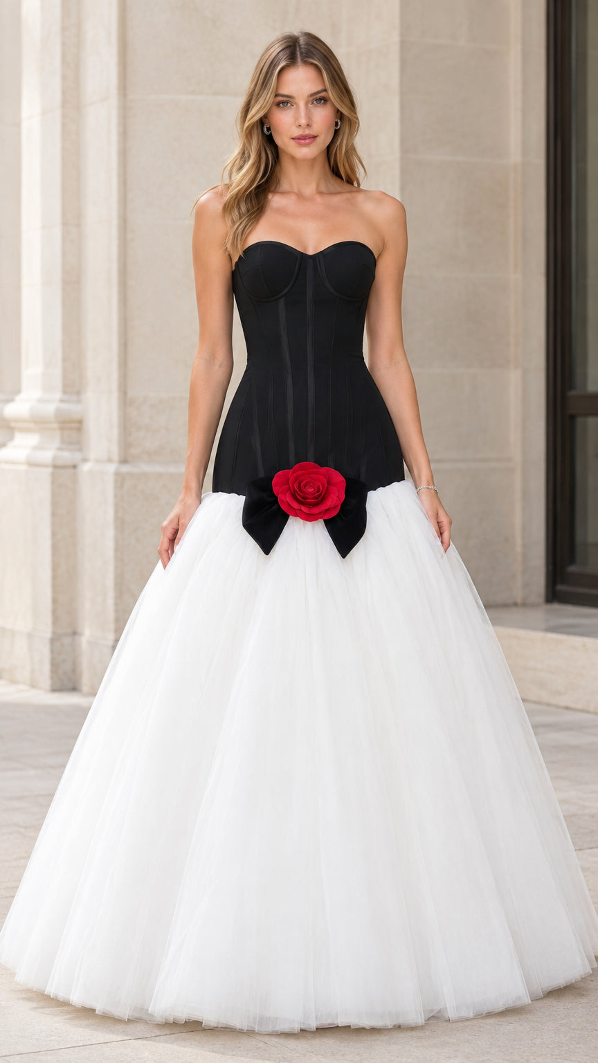 Front view of woman wearing strapless black corset ball gown with white tulle skirt and red rose detail