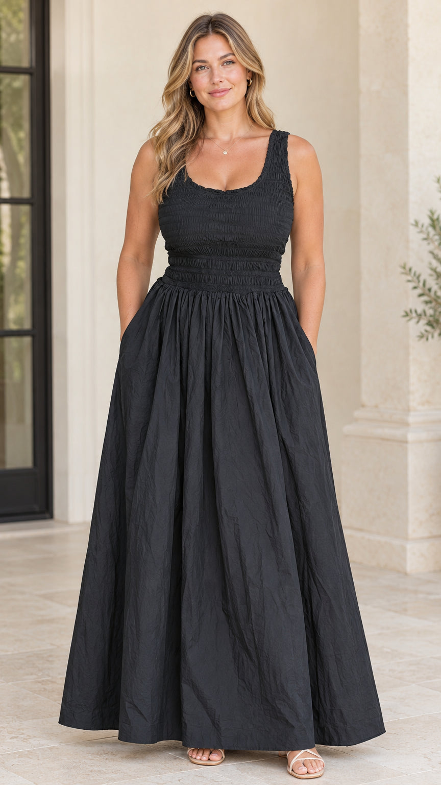 Front view of model wearing black sleeveless smocked bodice maxi dress with pockets