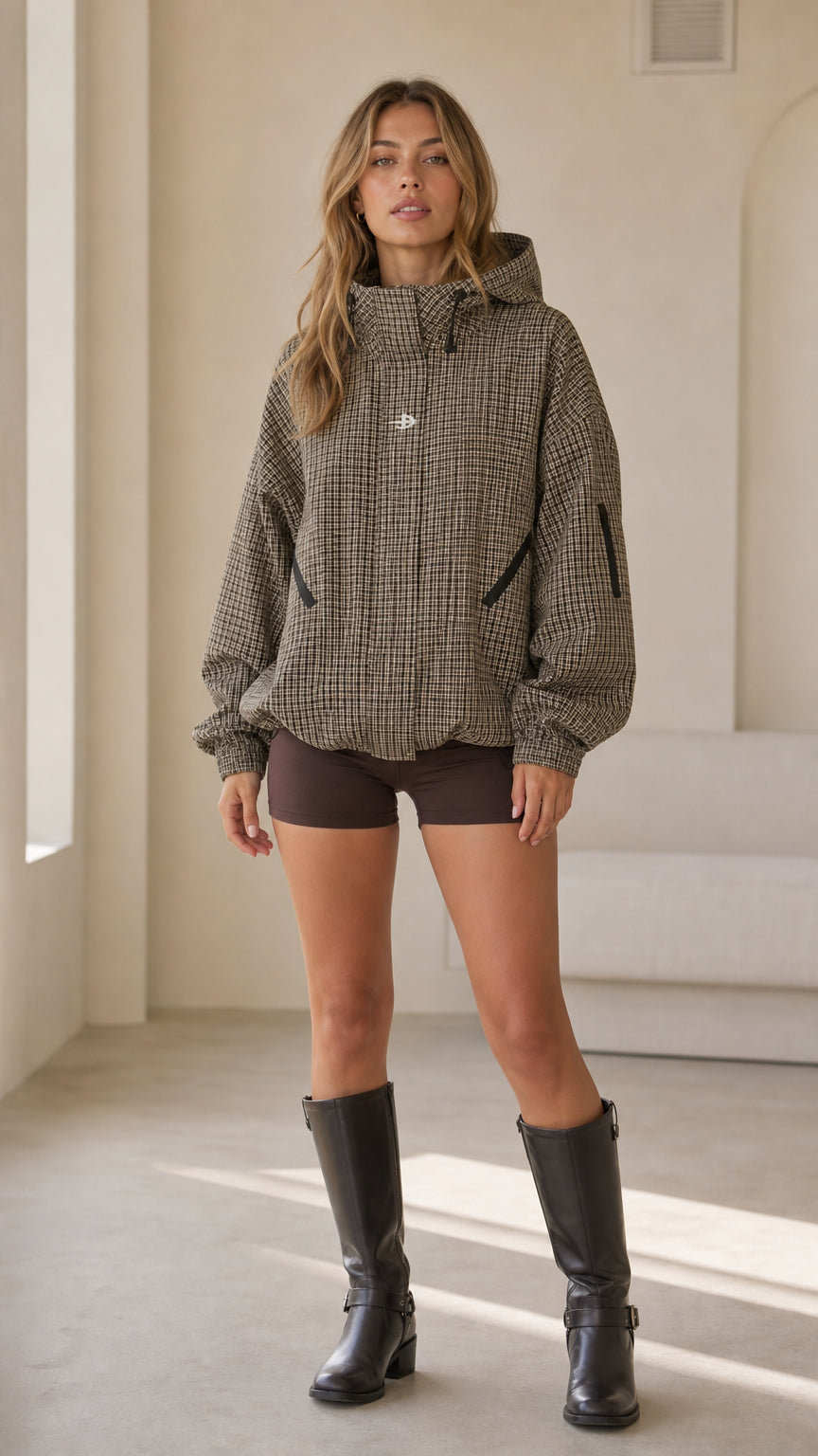 Front full view of woman wearing brown houndstooth oversized hooded jacket with boots