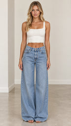 Front view of woman wearing high-rise light wash wide-leg denim jeans paired with white crop top