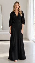 Front view of model wearing a black pleated V-neck maxi evening dress with flared sleeves