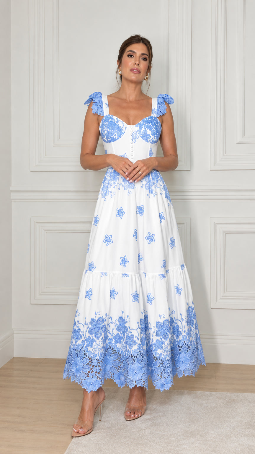 Front view of model wearing white tiered maxi dress with blue floral embroidery and scalloped lace hem